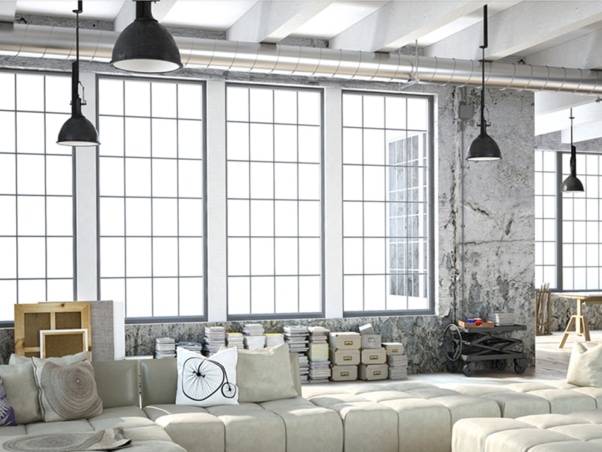 Loft industriel lumineux avec de grandes fenêtres, une décoration grise, des livres et des luminaires suspendus modernes : un studio parfait pour la créativité et l'innovation. Limbus Studio