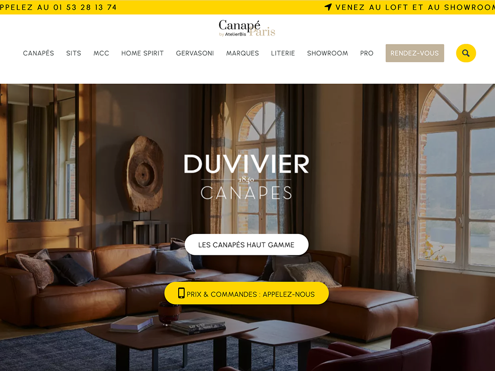 L'intérieur de la salle d'exposition, conçu avec un design expert, comprend des canapés en cuir, de grandes fenêtres et une table basse moderne sous un éclairage doux. Limbus Studio