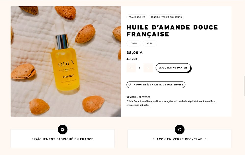 Une bouteille d'huile d'amande française au design élégant repose sur un tissu texturé, bordé de coquilles d'amandes. Une création élégante, dont les détails du produit et le prix sont présentés avec art. Limbus Studio