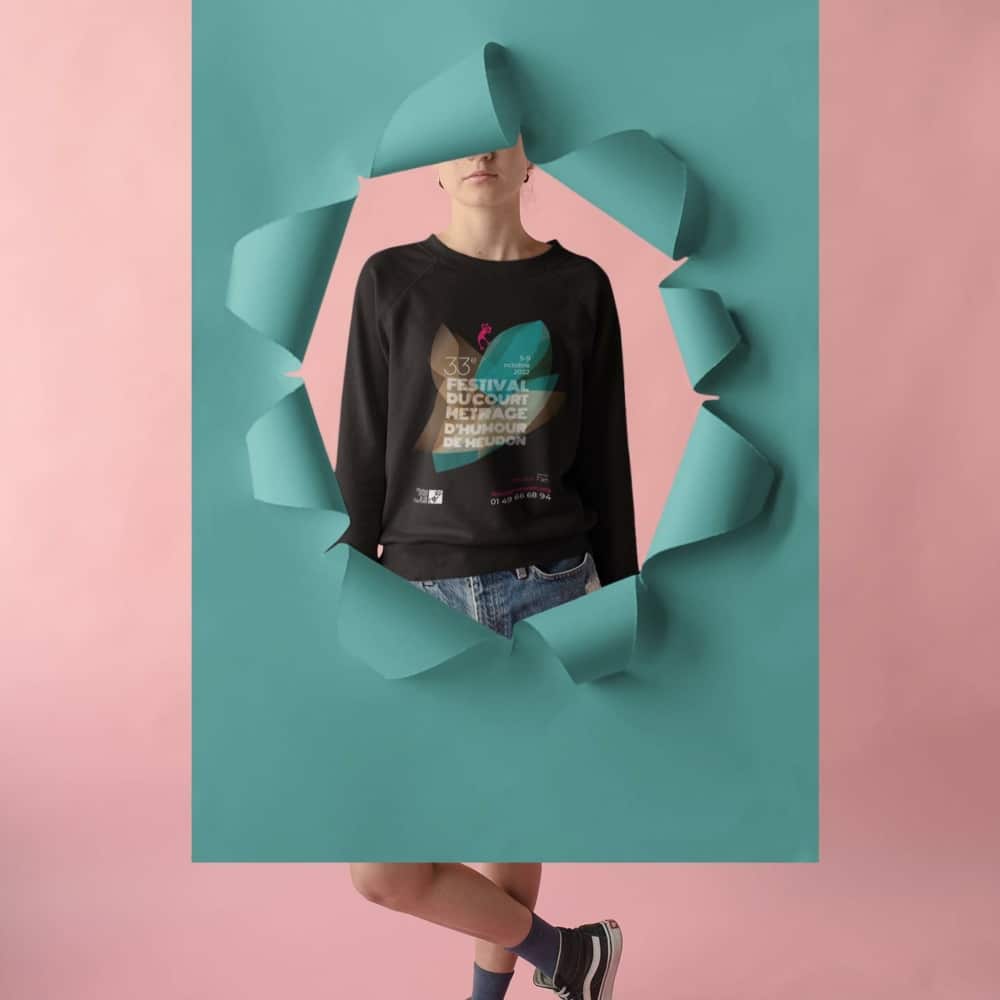Une personne portant un pull noir pose à travers une déchirure de papier bleu sarcelle sur un fond rose, incarnant un nouveau concept de design rappelant le style d'une agence innovante. Limbus Studio