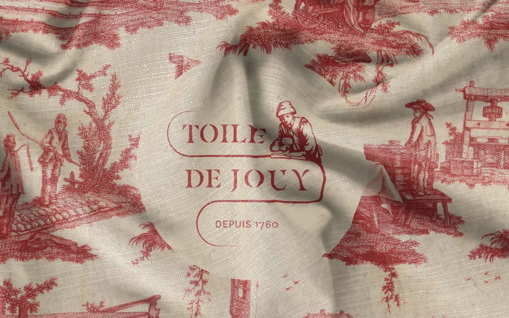 Tissu crème avec des scènes pastorales rouges et le texte "Toile de Jouy Depuis 1760" au centre, inspiré des motifs présentés au musée de la Toile de Jouy. Limbus Studio