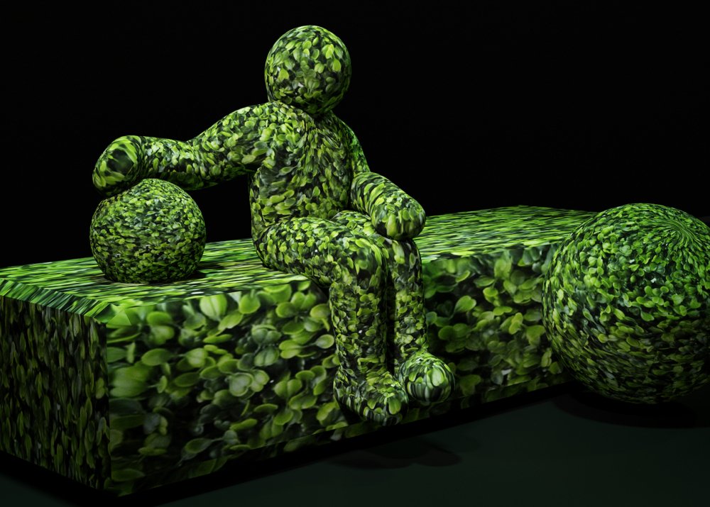 Une figure, magistralement conçue et recouverte de feuilles vertes, est assise sur un banc feuillu avec deux sphères feuillues à proximité. Limbus Studio