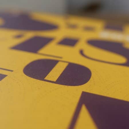 Gros plan d'une surface jaune avec de grandes lettres violettes audacieuses, présentant un design époustouflant qui incarne la créativité moderne. Limbus Studio