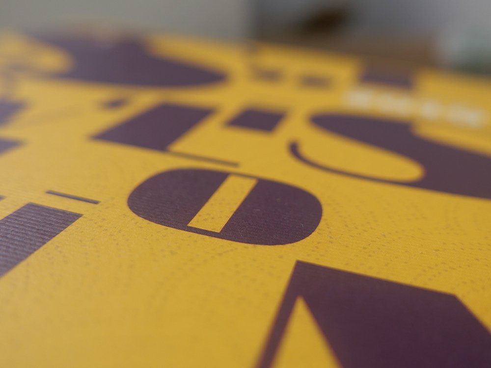 Gros plan d'une surface jaune avec de grandes lettres violettes audacieuses, présentant un design époustouflant qui incarne la créativité moderne. Limbus Studio